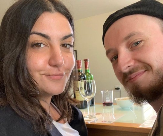 Almara Abgarian avec son petit ami, Alex, avec des bouteilles de vin/verres en arrière-plan