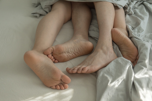 Pieds mâles et femelles au lit sous couvertures