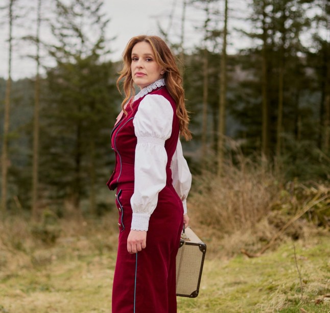 Katie Norris pose tout en tenant une valise