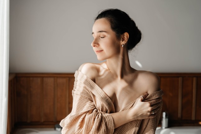 Une jeune femme dans un peignoir en mousseline se prépare à prendre un bain. Matin à l'hôtel, le concept de voyage et d'autosoins.