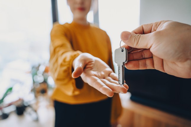 En gros plan d'un agent immobilier donnant à une jeune femme asiatique les clés de sa nouvelle maison. Concepts de propriété