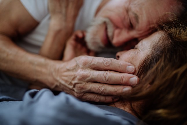 Gros plan d'un couple âgé allongé ensemble dans son lit.