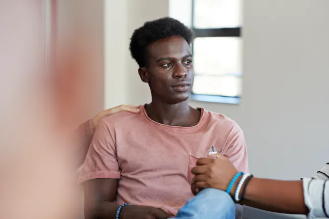 Jeune homme pleurant tout en étant consolé par des amis