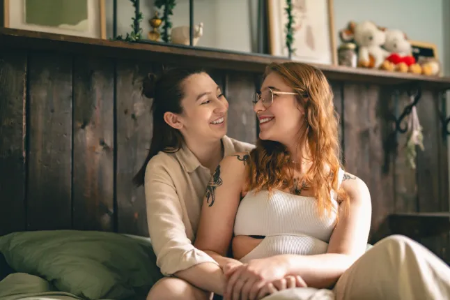 Heureux couple se blottissant sur leur lit à la maison, l'image montre deux femmes.