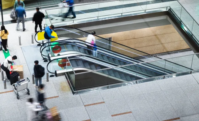 Groupe de personnes utilisant les escaliers mécaniques de l'aéroport