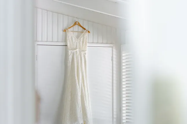 Robe blanche élégante accrochée à un cintre en bois dans une pièce lumineuse