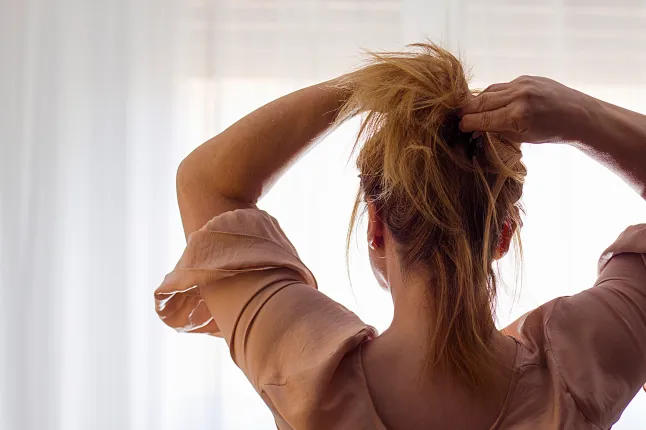 Femme par derrière ramassant ses cheveux