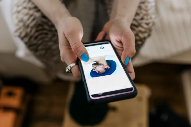 Les mains d'une femme tenant un téléphone affichant une application de rencontres