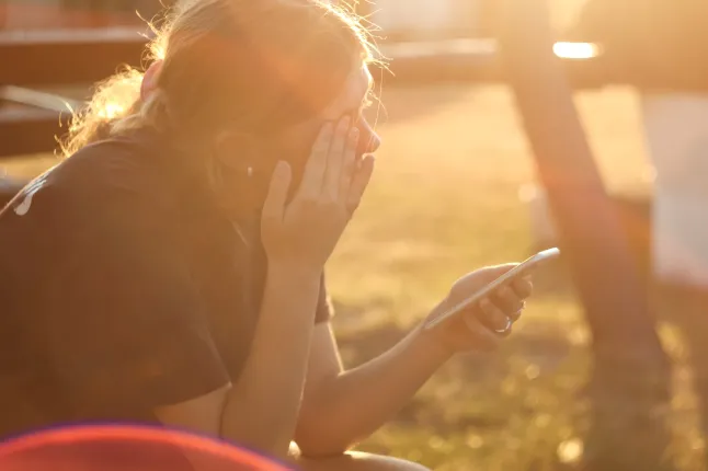 Cyberintimidation et harcèlement en ligne : une adolescente pleure avec un téléphone à la main, symbolisant le danger et la violence émotionnelle d'Internet