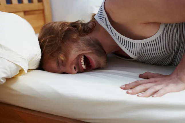 Plan intime mi-longueur d'un homme séduisant riant et poussant sa tête vers le lit