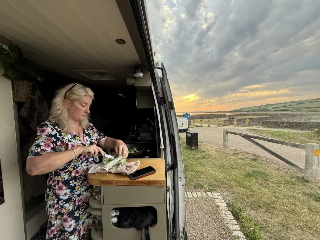 Kath Cross dans le sud du Pays de Galles. // Un couple a vendu tous ses biens pour acheter un camping-car et parcourir le monde - pour seulement 30 euros par jour. Kath Cross, 49 ans, et Stuart Hall, 48 ans, ont parcouru plus de 25 000 milles dans des aventures épiques à travers le désert du Sahara, l'Europe et l'Écosse dans leur camping-car. Le couple vit dans leur Mercedes Sprinter de 7,5 millions de mètres depuis que Kath a vendu tous ses biens et a arrêté de payer son loyer il y a quatre ans. À ce jour, ils ont visité plus de 15 pays – et en auront dépassé 20 au moment où ils reviendront de leur voyage actuel au Monténégro. Photo publiée le 05/07/2026