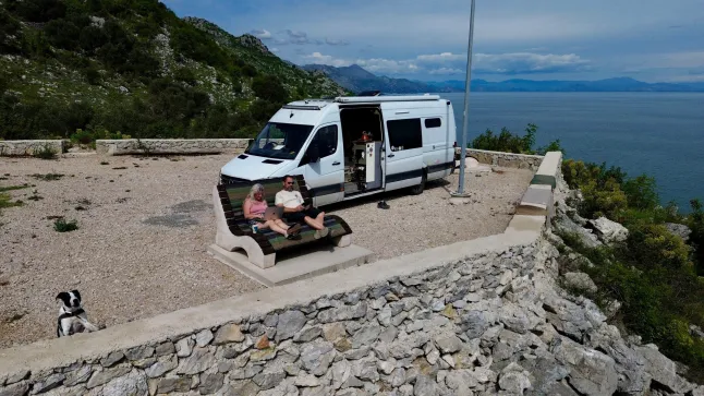 Kath Cross et Stuart Hall à côté de leur camionnette. // Un couple a vendu tous ses biens pour acheter un camping-car et parcourir le monde - pour seulement 30 euros par jour. Kath Cross, 49 ans, et Stuart Hall, 48 ans, ont parcouru plus de 25 000 milles dans des aventures épiques à travers le désert du Sahara, l'Europe et l'Écosse dans leur camping-car. Le couple vit dans leur Mercedes Sprinter de 7,5 millions de mètres depuis que Kath a vendu tous ses biens et a arrêté de payer son loyer il y a quatre ans. À ce jour, ils ont visité plus de 15 pays – et en auront dépassé 20 au moment où ils reviendront de leur voyage actuel au Monténégro. Photo publiée le 05/07/2026