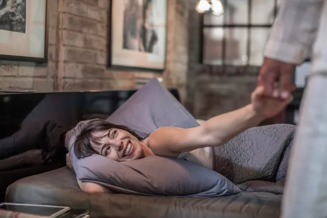 Femme souriante au lit regardant son mari