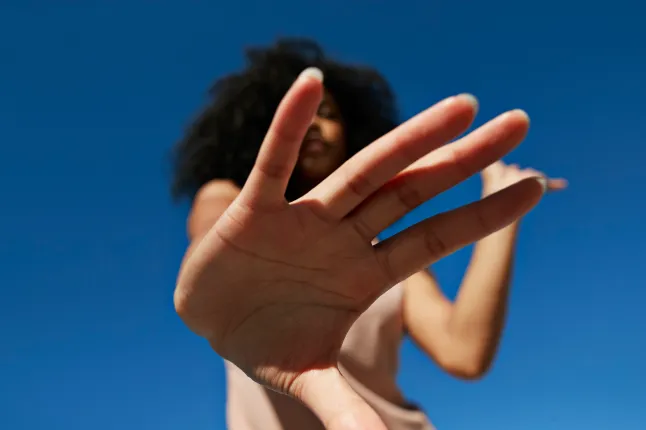 Sportive montrant un geste d'arrêt contre un ciel bleu clair