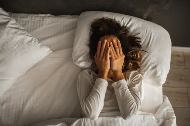 Femme en dépression, visage fermé avec les mains et pleurant au lit. Humeur mélancolique, santé mentale. Problèmes de vie