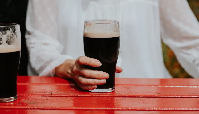 Gros plan d'une femme tenant une pinte de Stout
