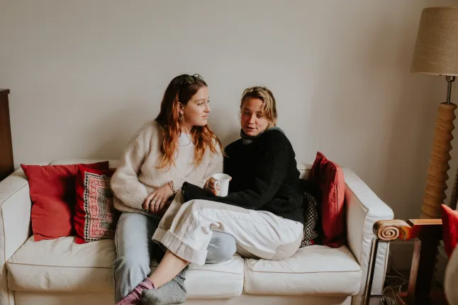 Deux femmes sont assises l'une près de l'autre sur un canapé et discutent sérieusement