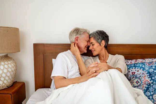 Couple de personnes âgées aimantes s'embrassant dans un cadre de chambre confortable et confortable