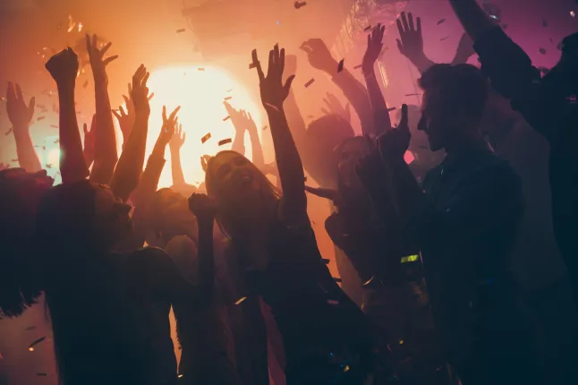 Photo de nombreux fêtards copains dansant des lumières jaunes confettis volant partout discothèque événement mains levées porter des vêtements brillants