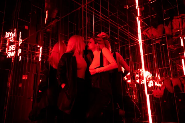 Des amies s'embrassant en se tenant debout dans une salle lumineuse rouge