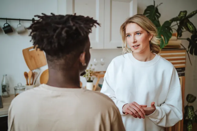 Couple de sexe opposé debout face à face et parlant dans la cuisine.