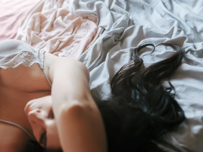 Fille brune pensive avec des cheveux formant un coeur allongé sur le lit