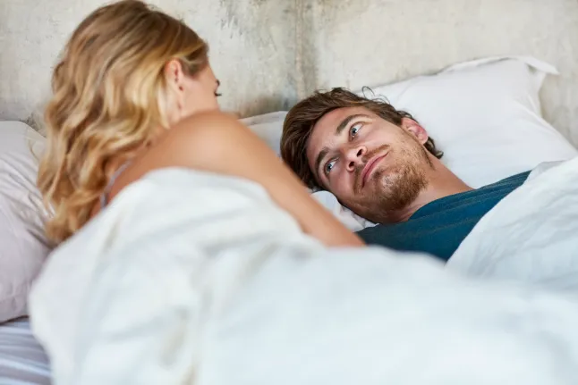 Un homme d'âge millénaire regarde avec amour sa partenaire féminine au lit.
