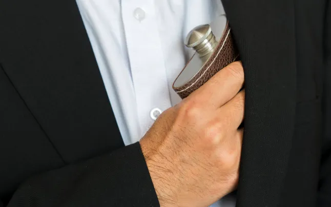 main prenant une bouteille de vin portable dans la poche de la chemise