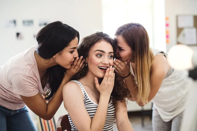 Trois femmes se murmurent à l'oreille.