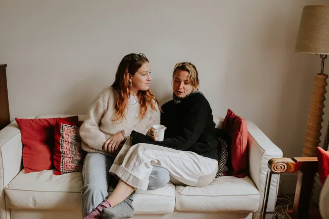 Deux jeunes femmes s'agrippent sur un canapé, discutent sérieusement et se soutiennent mutuellement.