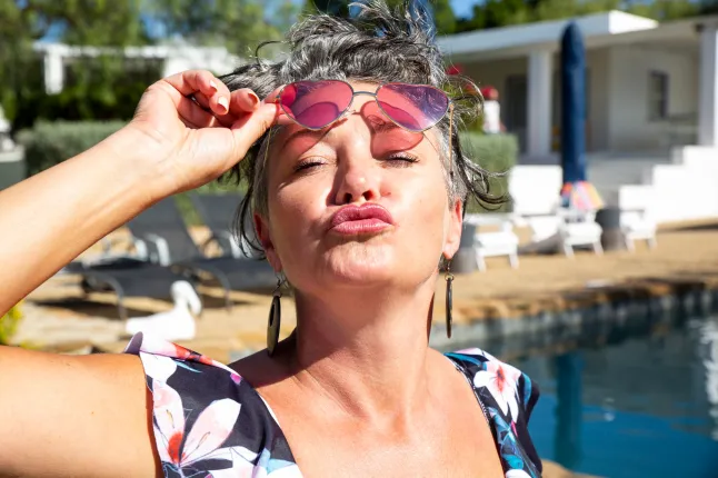 Femme portant des lunettes de soleil et plissant par une journée ensoleillée.