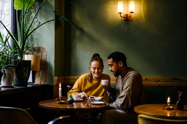 Plan large avec espace de copie d'un couple ayant des cappuccinos et un cheesecake dans un café
