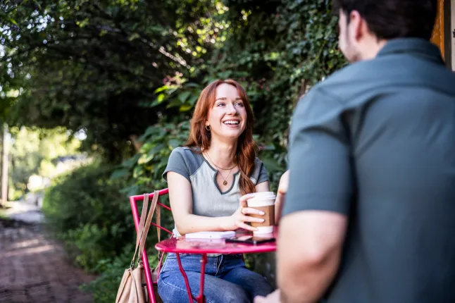 Jeune couple parlant à la table du café en plein air