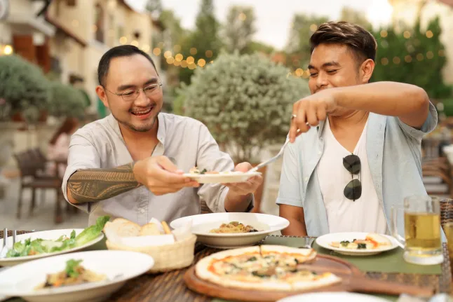 Un homme prenant soin de son petit ami servant des repas tout en dînant au restaurant