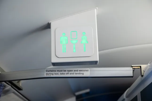 Panneau de toilettes/toilettes sur un avion commercial. Le panneau est vert indiquant que la cabine est vide et disponible pour utilisation