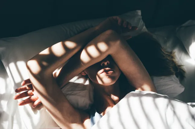 Femme triste et déprimée allongée dans son lit à la maison.