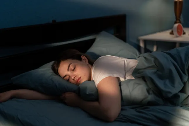 Jeune femme dormant paisiblement dans sa chambre la nuit. Détente la nuit. Espace de copie