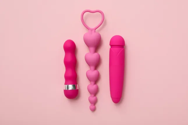 Collection de jouets sexuels, sur fond rose.