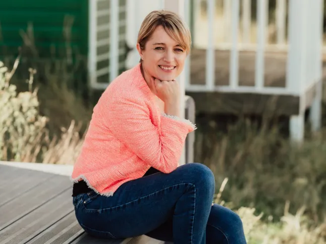 Gillian Harvey assise dehors sur la terrasse d'une maison, souriante et posant son menton sur sa main