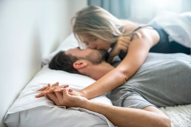 Le jeune couple s'embrassant dans le lit