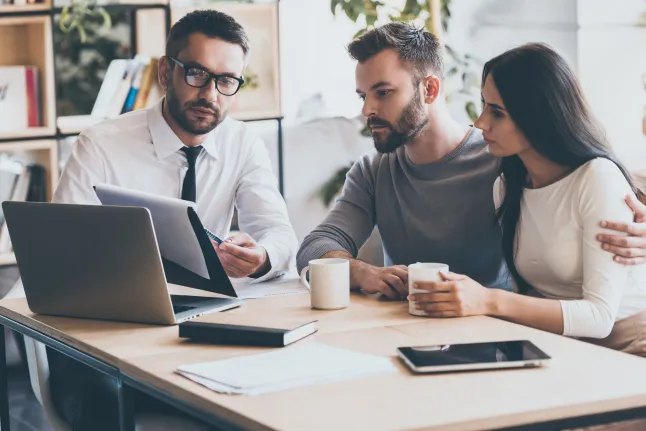 J'ai besoin de votre signature ici. Jeune homme confiant en chemise et cravate tenant un document et le pointant tout en étant assis avec un jeune couple au bureau ; Numéro d'identification Shutterstock 431846191 ; commande_achat : - ; emploi: -; client: -; autre: -
