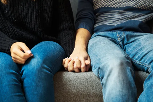couple anonyme assis sur le canapé se tenant la main