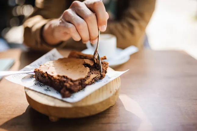 Personne méconnaissable mangeant un brownie.