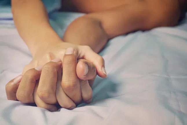 Un gros plan des mains d'un homme et d'une femme jointes au lit