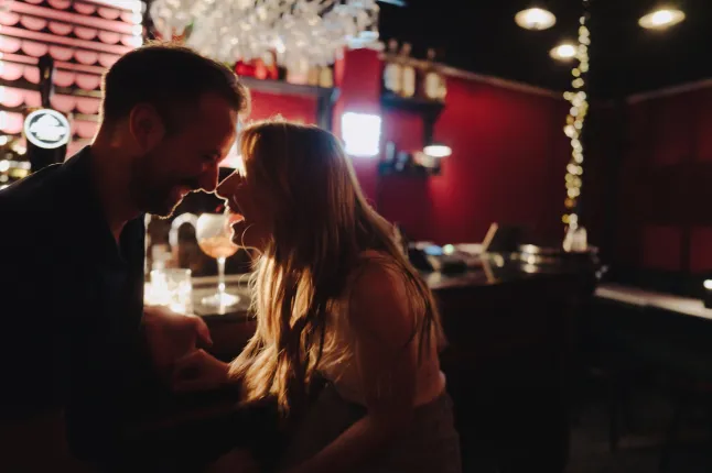 Photo d'un couple prenant un verre et riant dans un bar sous des lumières d'ambiance