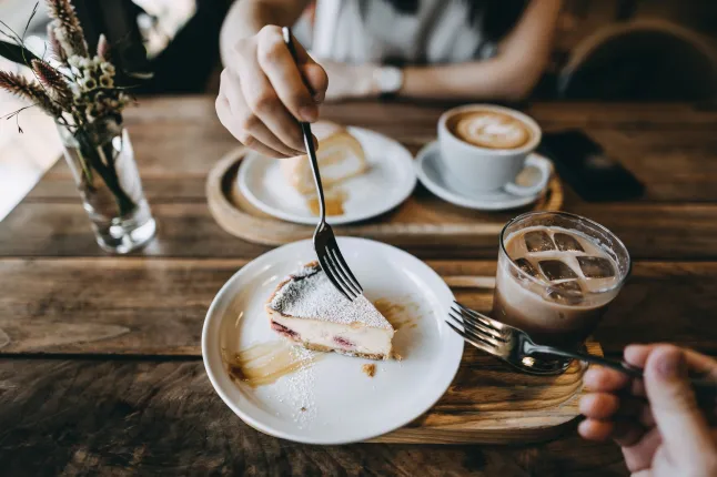 Jeune couple s'amusant en dégustant un café et un gâteau dans un café