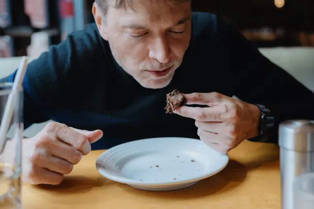 Gros plan d'un homme d'âge moyen finissant un brownie au fudge au restaurant